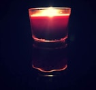 Artful shot of a burning candle casting warm shadows on a charcoal and cream textured surface.
