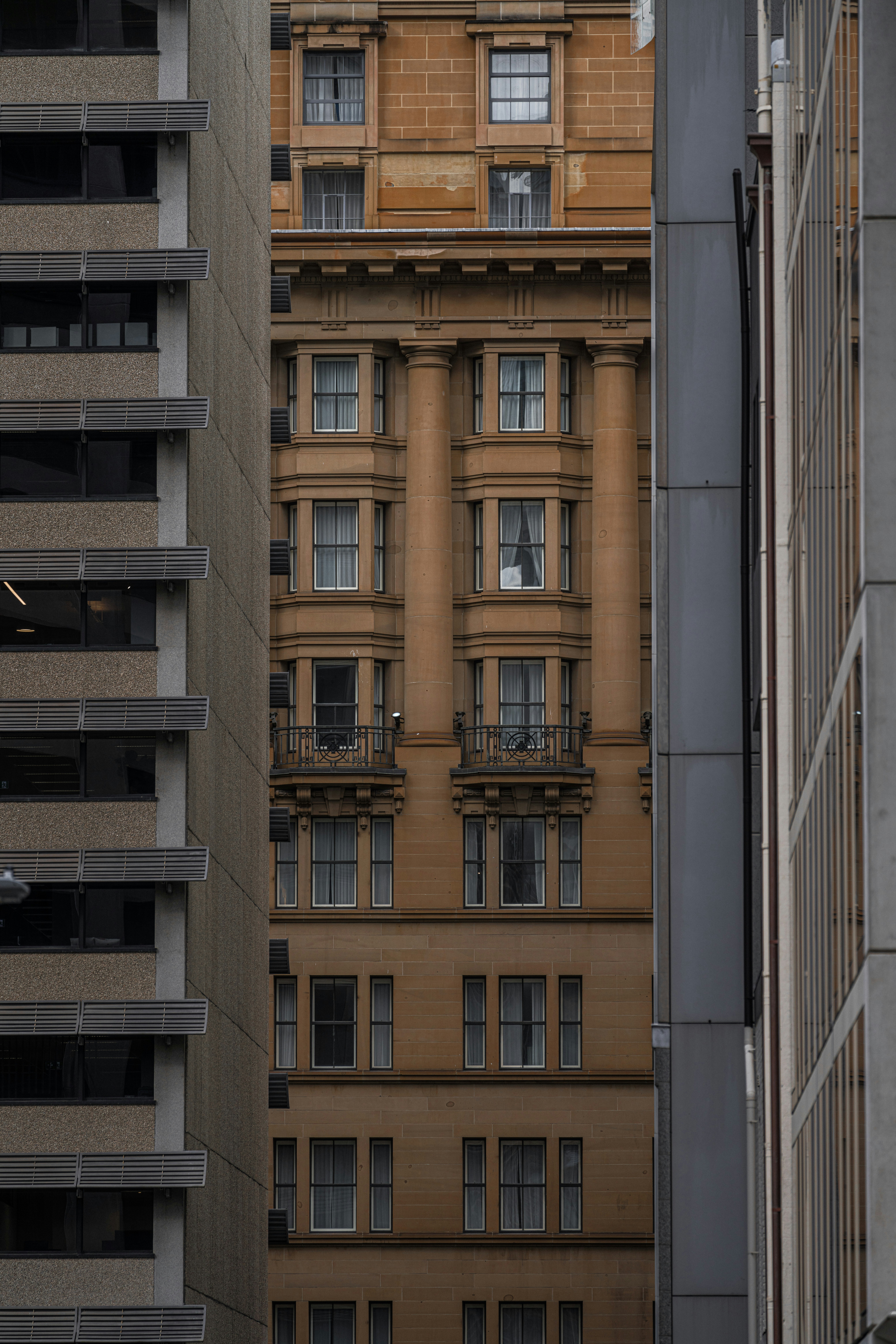 Old building peaking out between two new buildings in Sydney