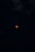 A dark night sky filled with stars surrounds a vivid red moon at the center, evoking a sense of mystery and tranquility. The moon's color suggests a lunar eclipse, creating a striking contrast against the darkness.