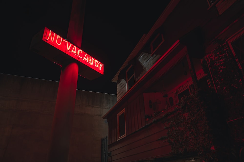 a red neon sign is lit up in the dark