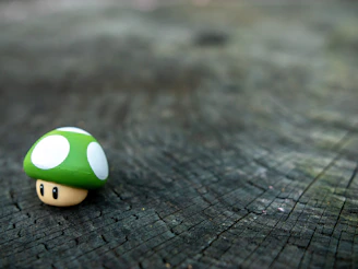 Close-up of a delicate handmade mushroom soft toy with embroidered details resting on a bed of toadstools.