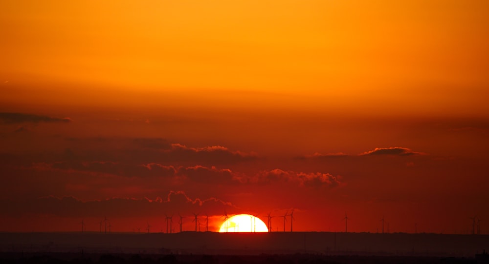 the sun is setting over a field with windmills