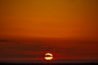 A golden-hued sunset behind wind turbines, reflecting the blend of technology and nature.