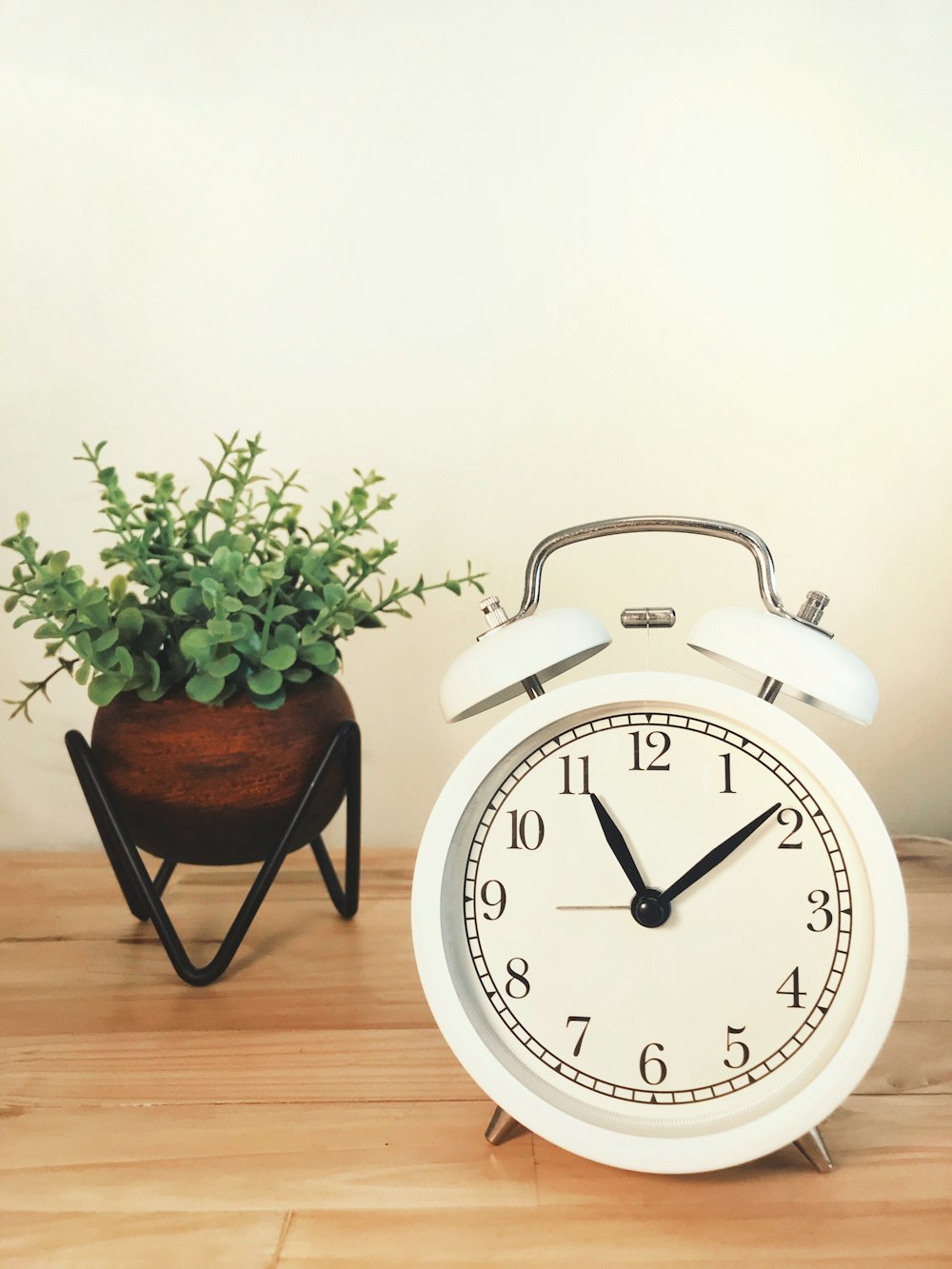 a white alarm clock sitting next to a potted plant