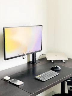 A minimalist workspace featuring a monitor displaying PDF icon thumbnails against a soft background.
