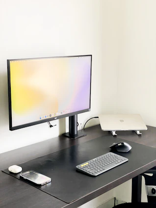 A minimalist workspace featuring a glowing AI neural network visualization on a sleek monitor.
