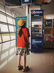 a young girl standing in front of a vending machine
