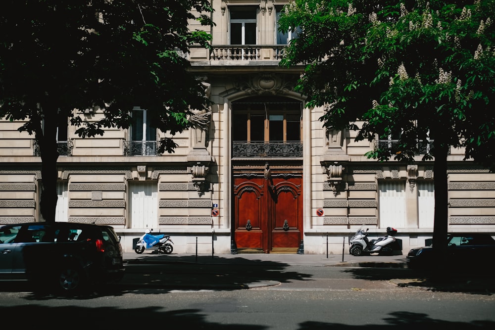 a large building with a red door and two cars parked in front of it