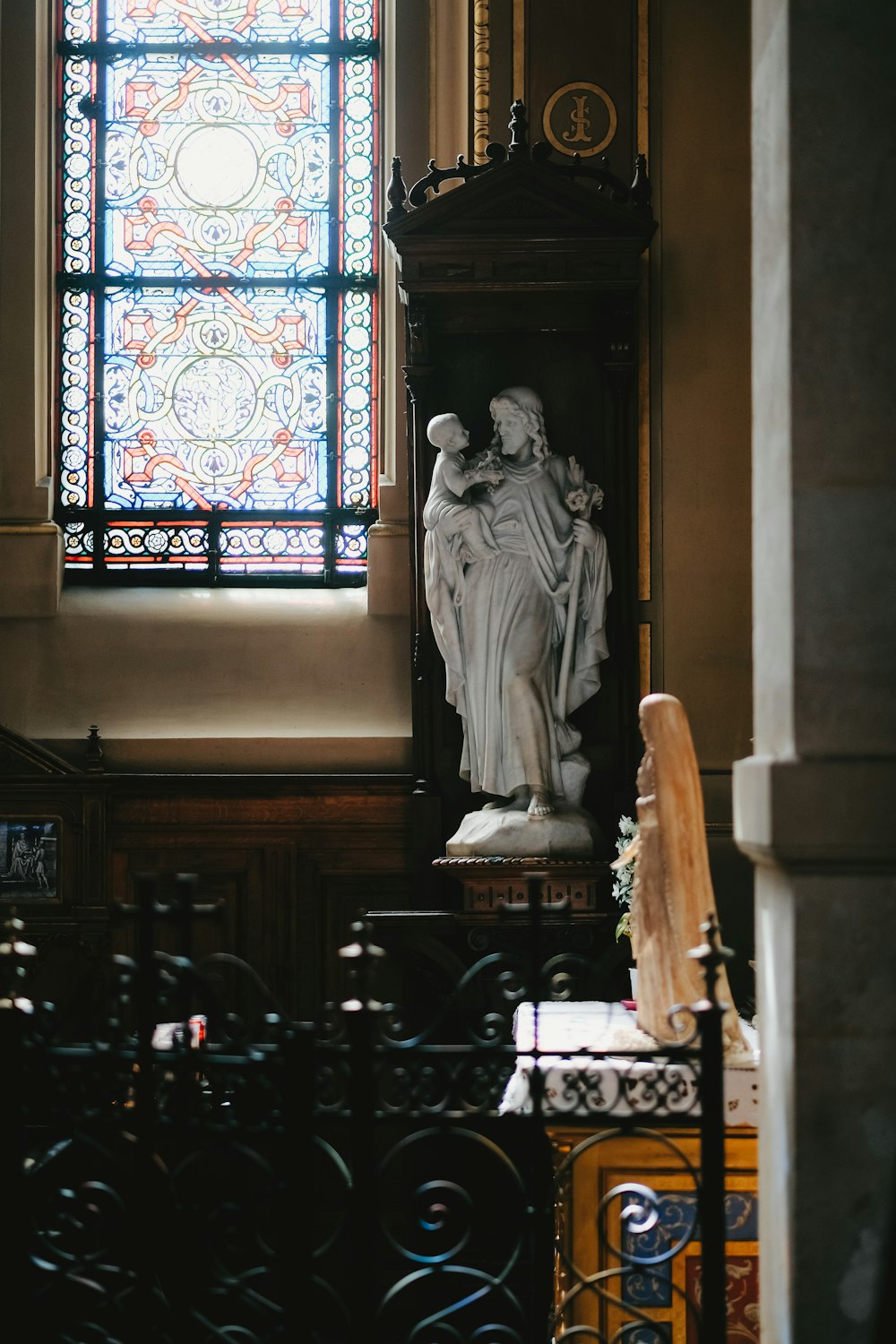 a statue in front of a stained glass window