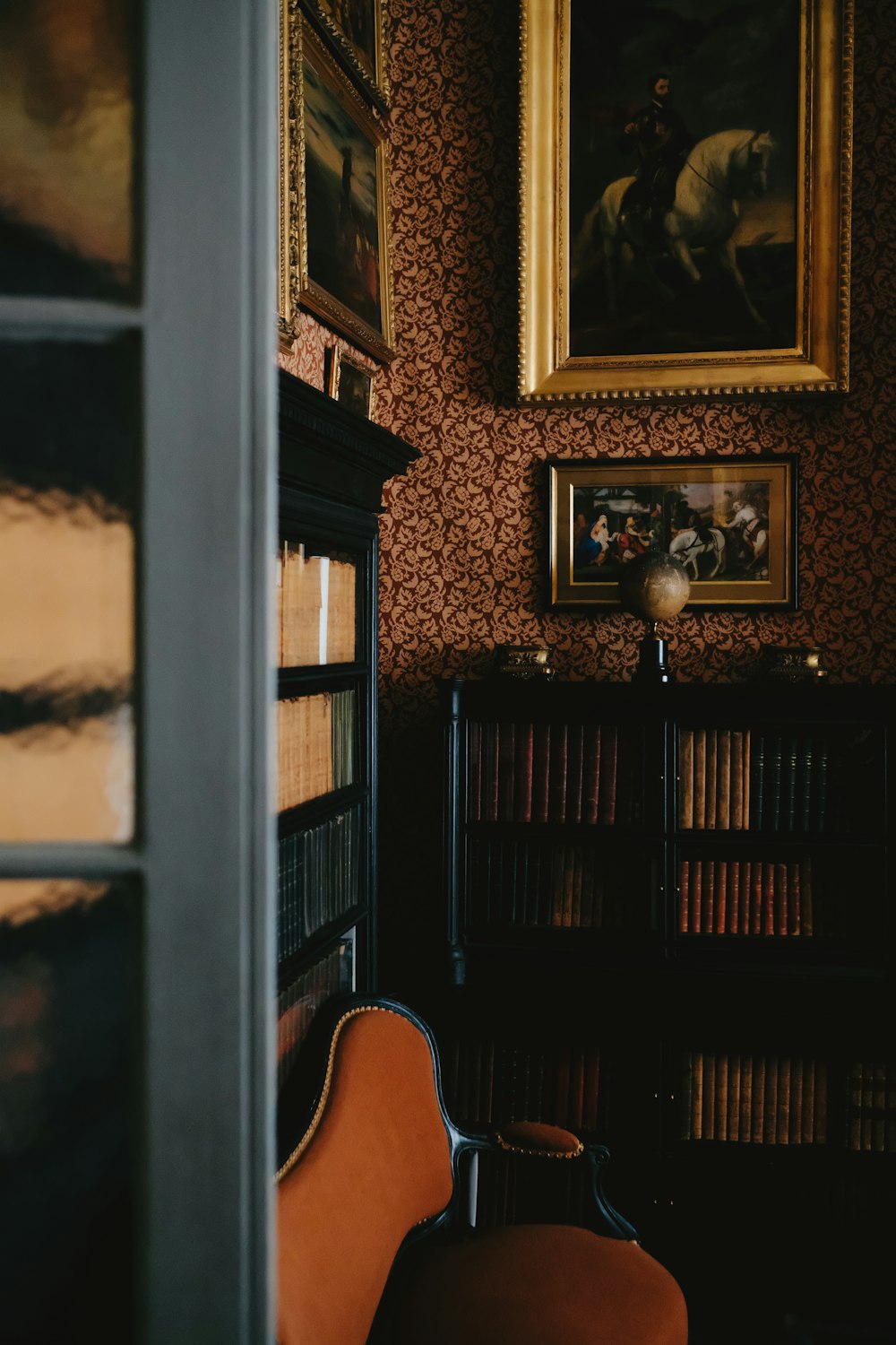 a room with a chair, bookshelf and a painting on the wall