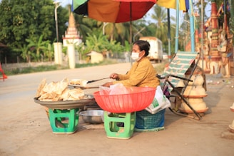 The Hungry Traveller: Food Adventures in Cambodia a woman sitting at a table with food on it