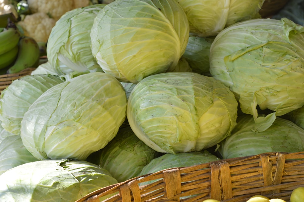a basket filled with cabbage next to a pile of green apples