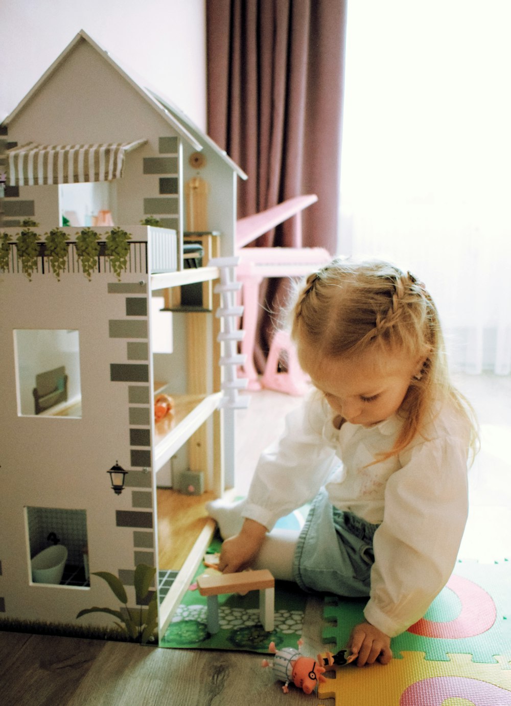a little girl playing with a doll house