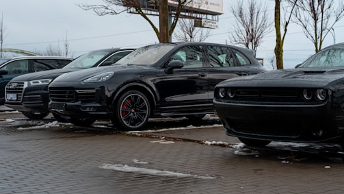 A row of clean cars with new wipers parked outside a busy office building.