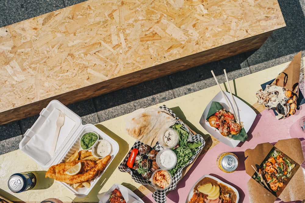 ein Tisch mit viel Essen neben einer Holzbank