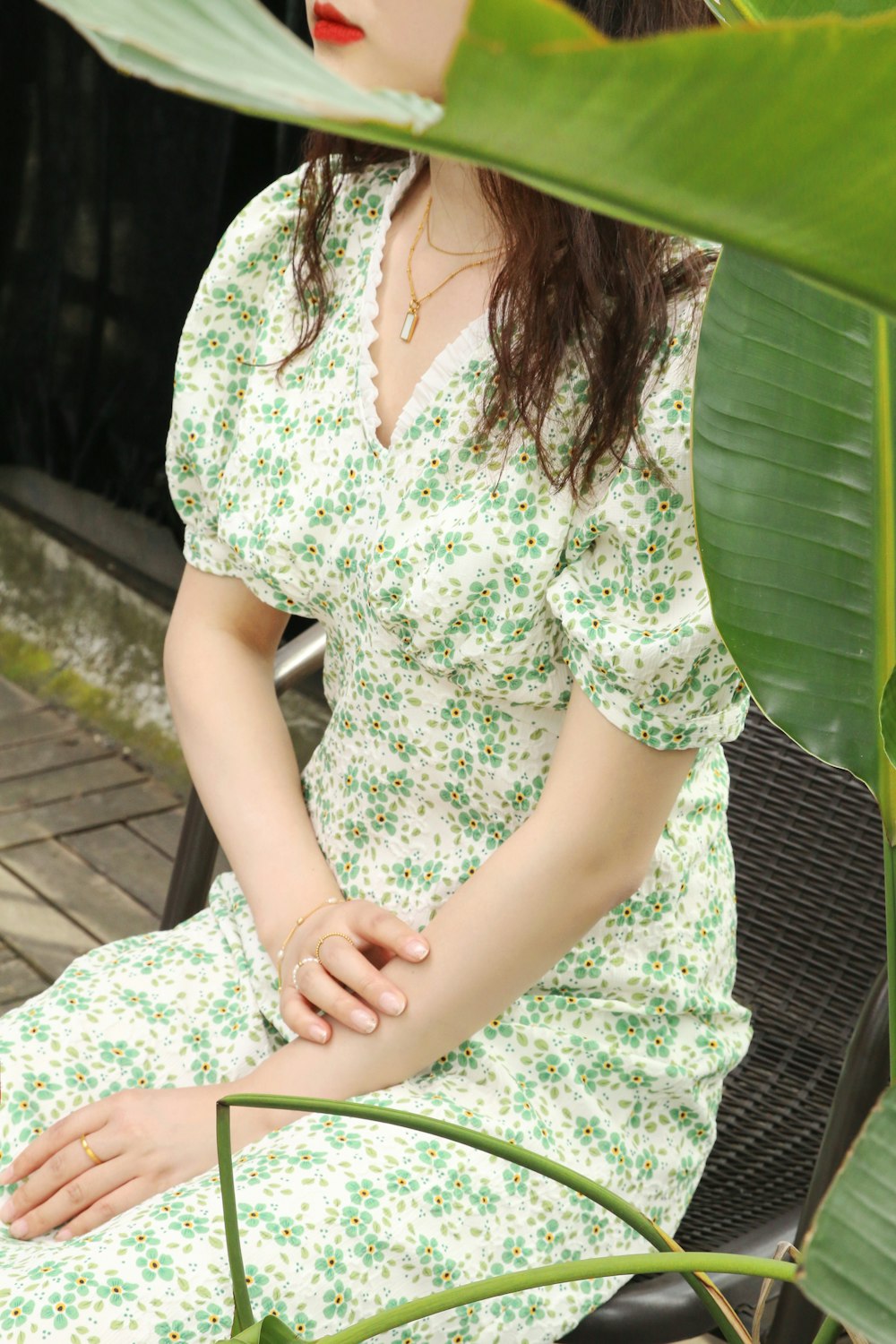 a woman sitting on a bench next to a plant