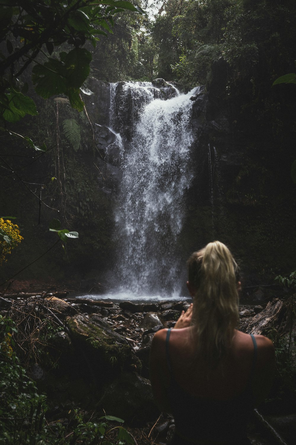 a woman sitting in front of a waterfall