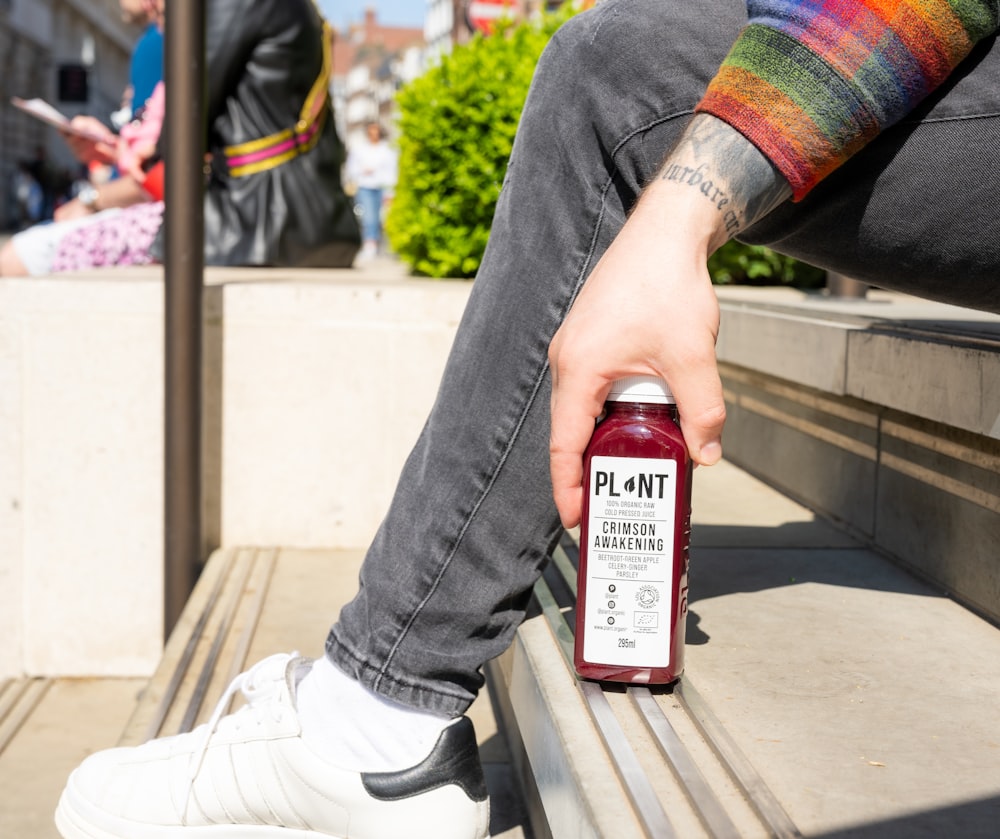 a person sitting on a bench with a bottle of juice