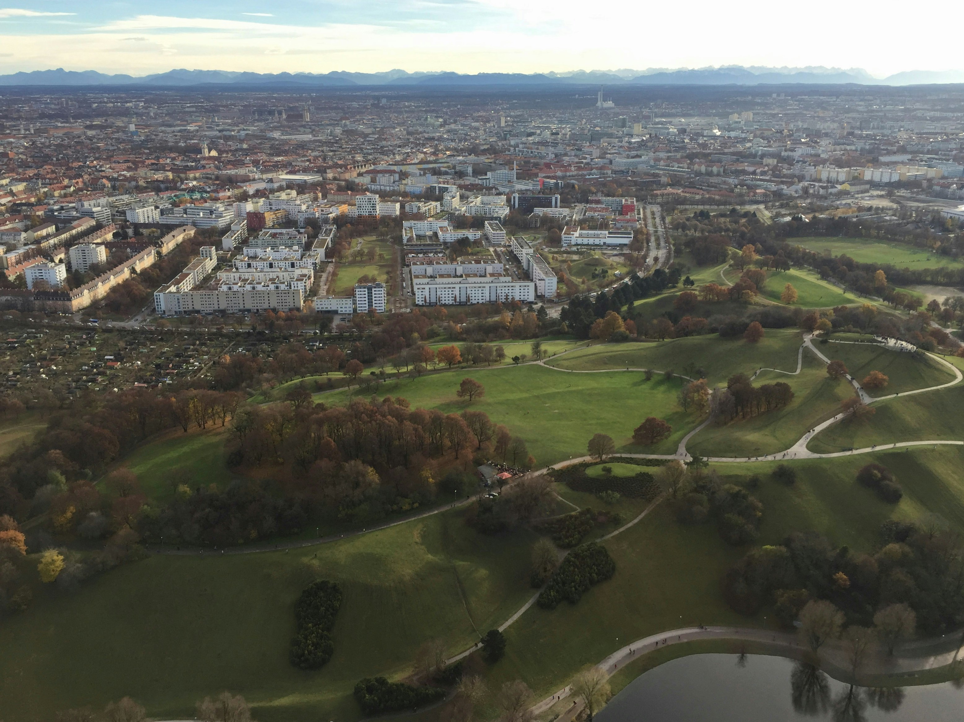an aerial view of a city with lots of trees, A top shot of the famous Olympiaturm in Munich, Germany
