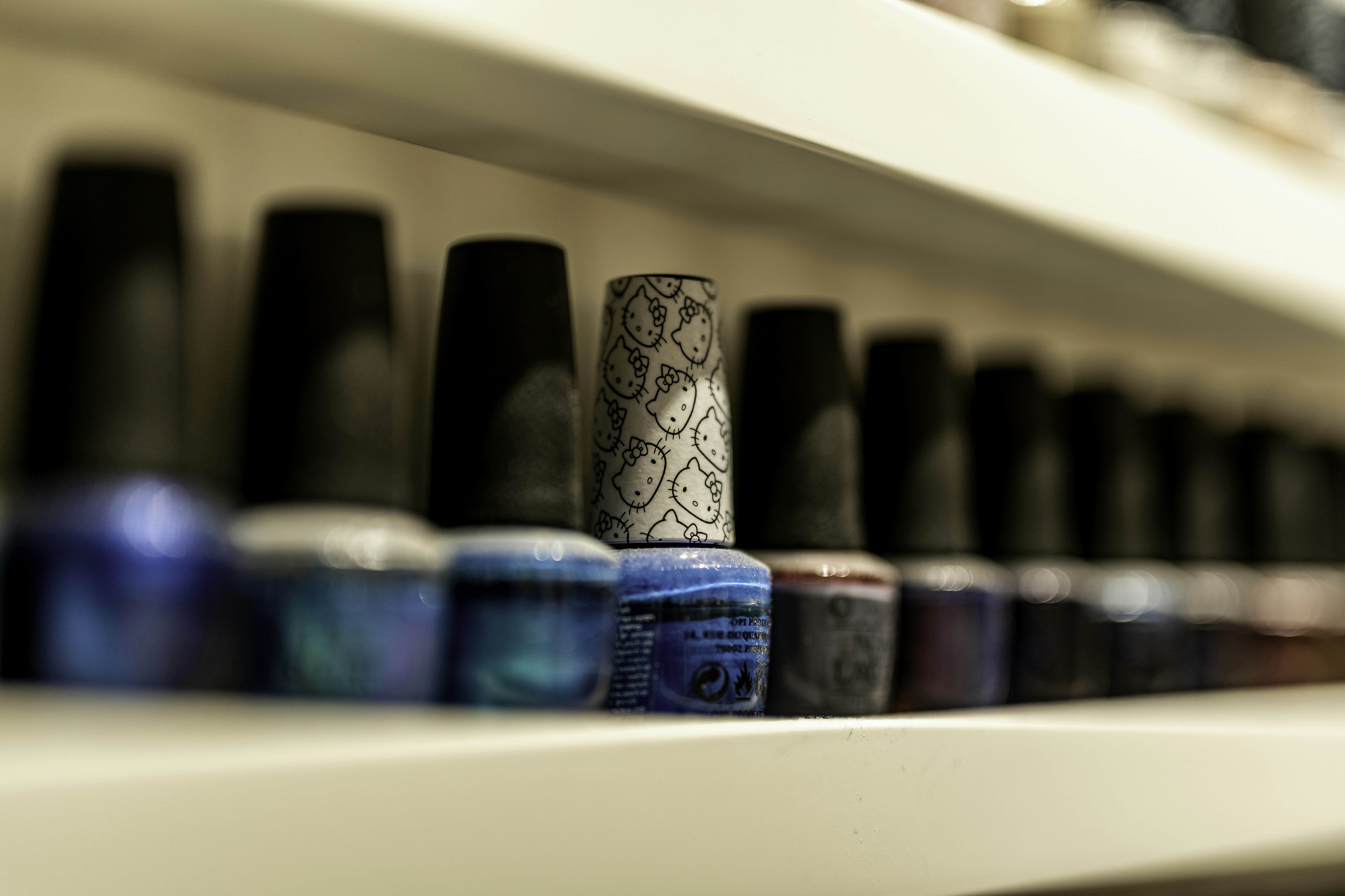 a row of bottles of nail polish sitting on top of a shelf