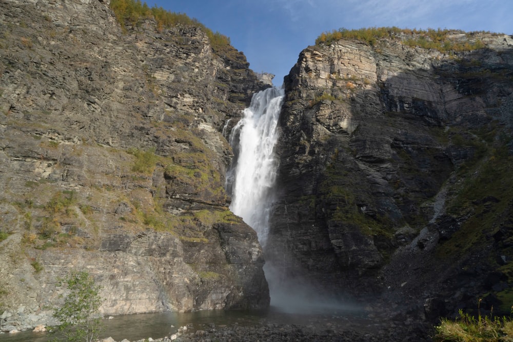 a large waterfall with a man standing in front of it