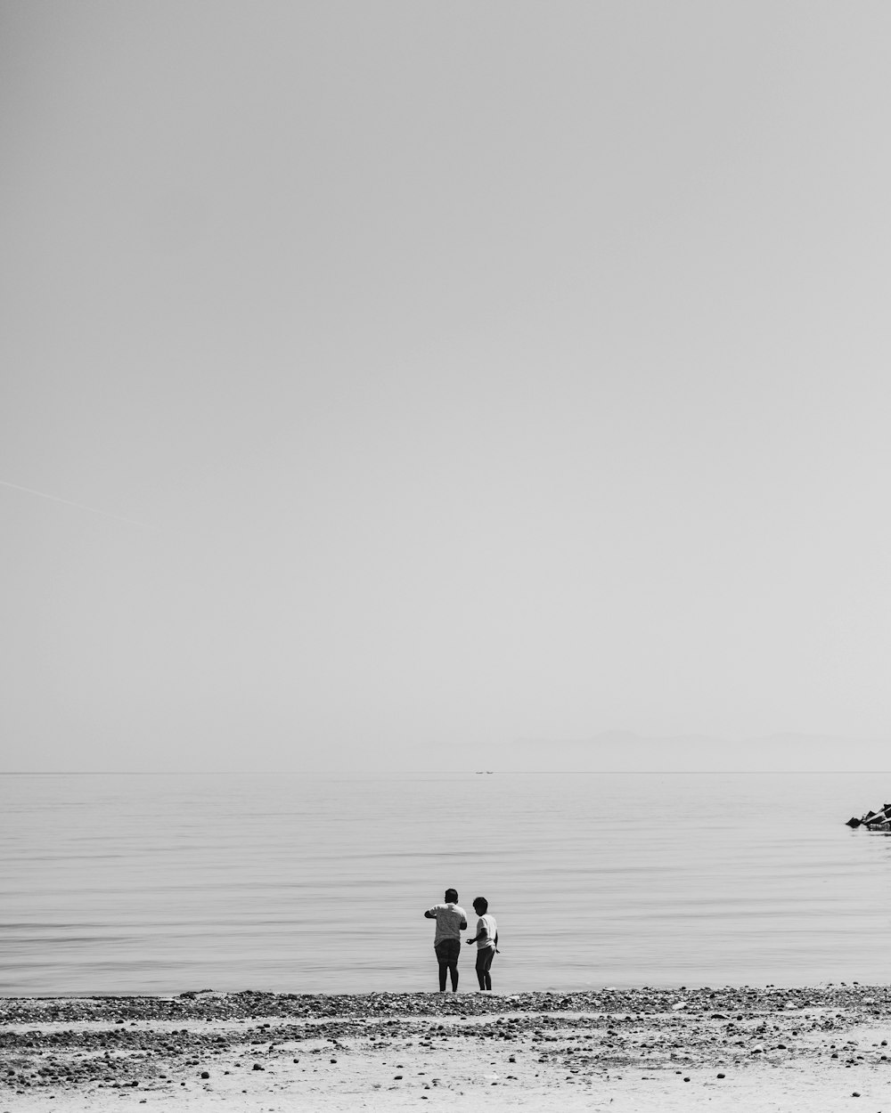 a couple of people standing on top of a sandy beach