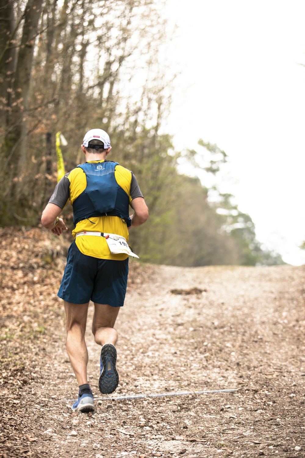 a man running down a dirt road in the woods