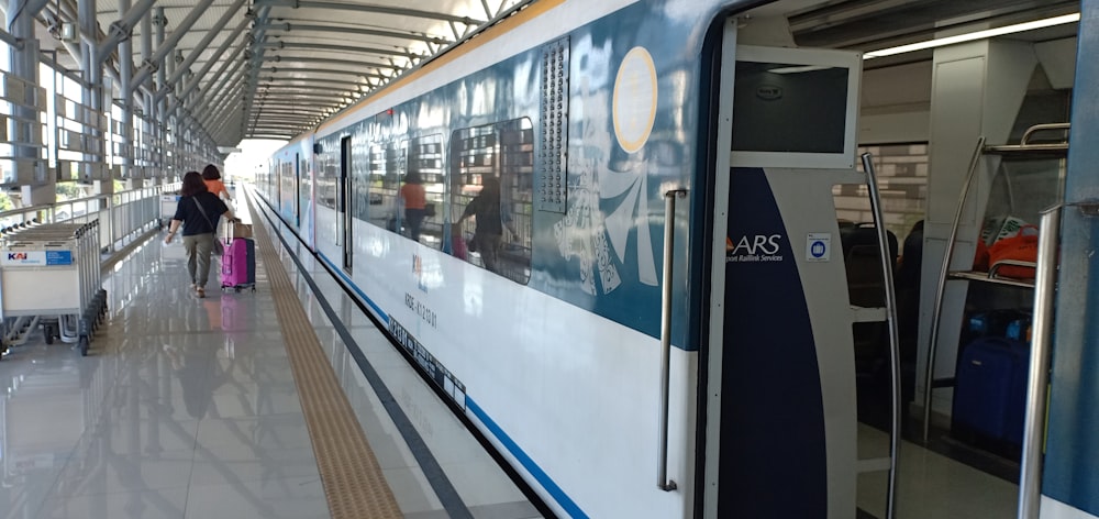 a train stopped at a train station with people walking by