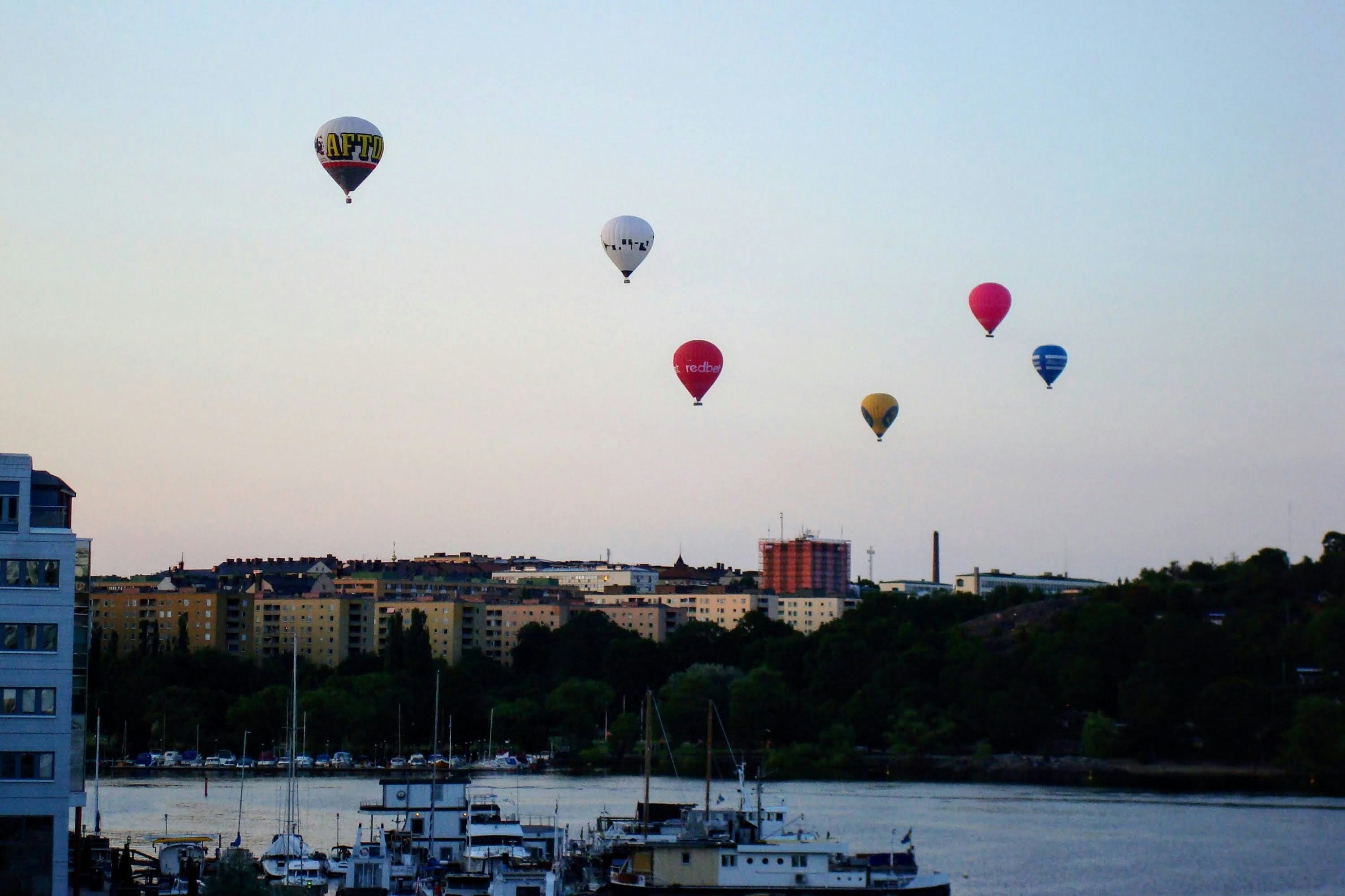 a group of hot air balloons flying over a harbor