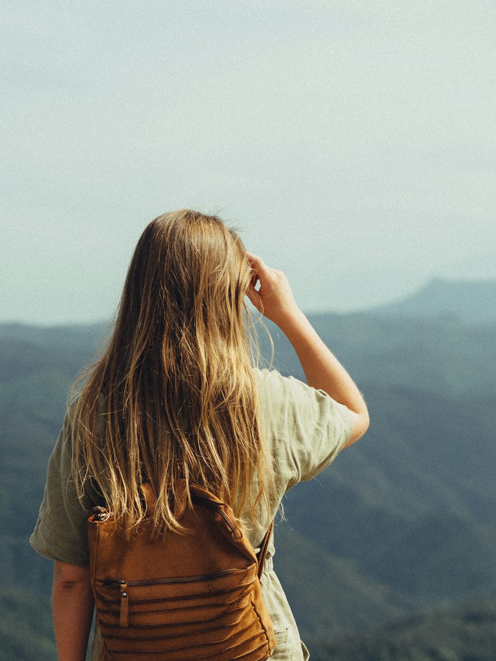 a woman standing on top of a lush green hillside