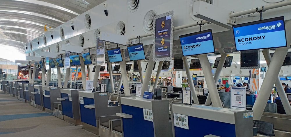 uma fileira de balcões de check-in electrónicos num aeroporto