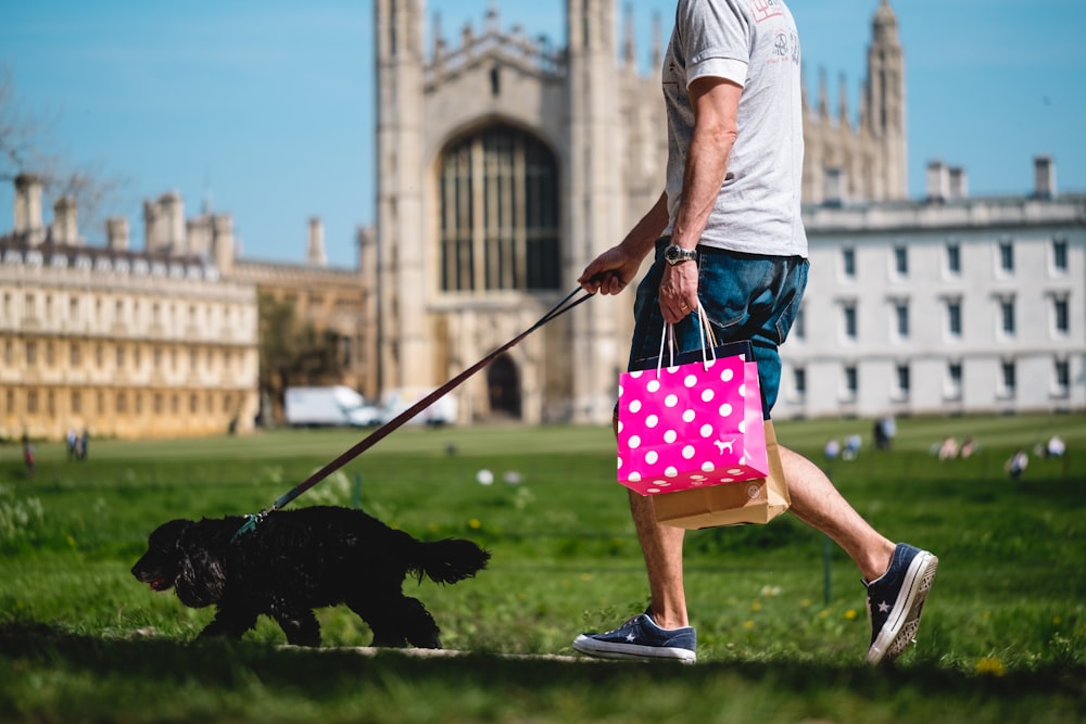 a man walking a black dog on a leash