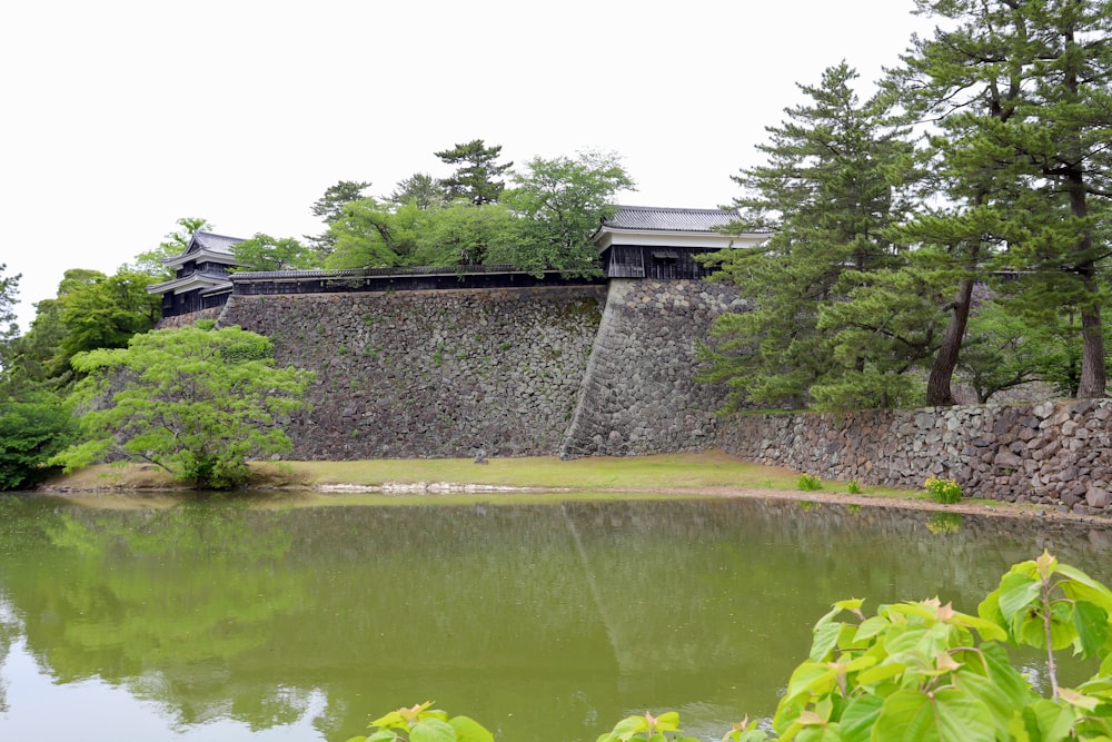 a pond in front of a stone wall