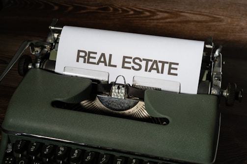 a close up of a typewriter with a real estate paper on it