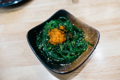 A colorful dish featuring seaweed salad garnished with sesame seeds and fresh vegetables.