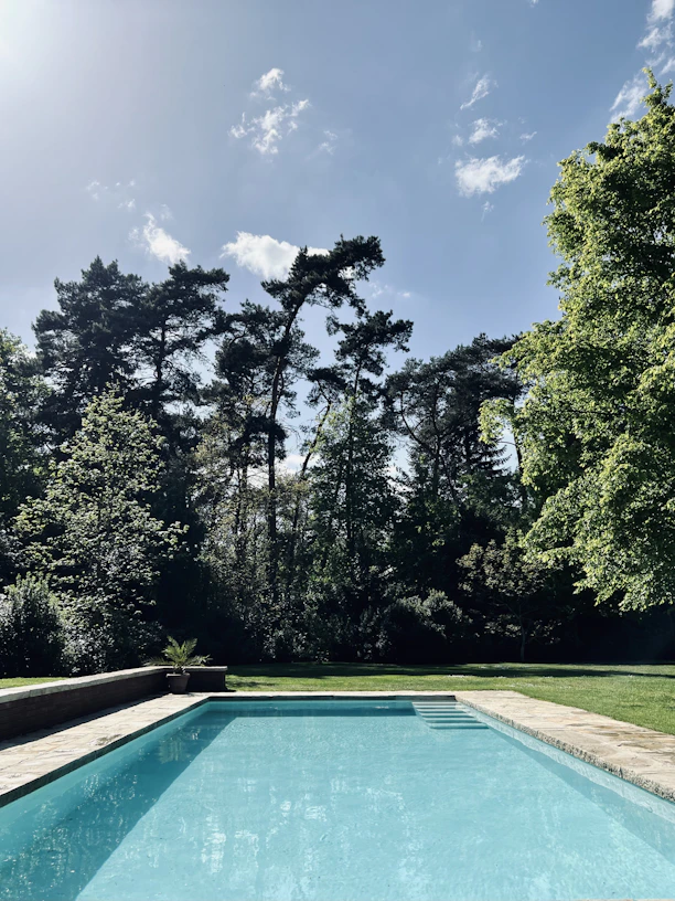 a swimming pool surrounded by trees and grass