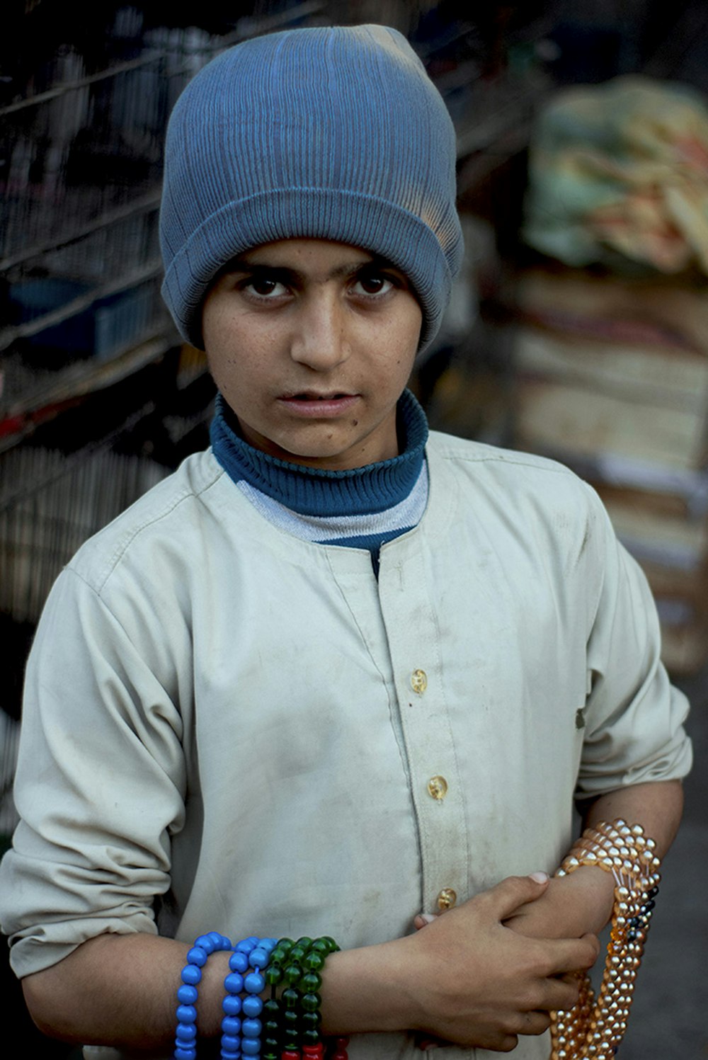 a young boy wearing a blue hat and bracelets