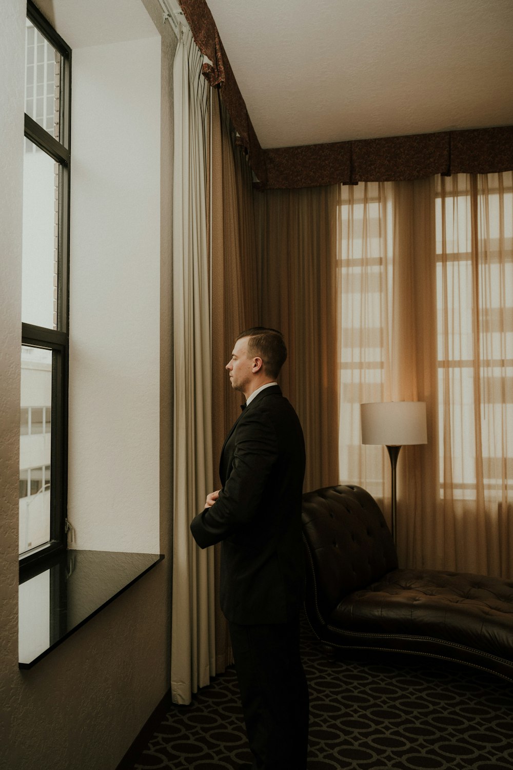 a man in a suit looking out a window