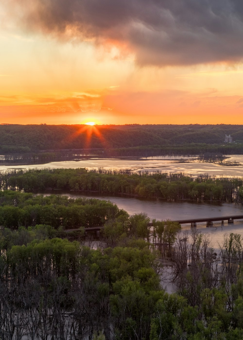 the sun is setting over a river and a bridge