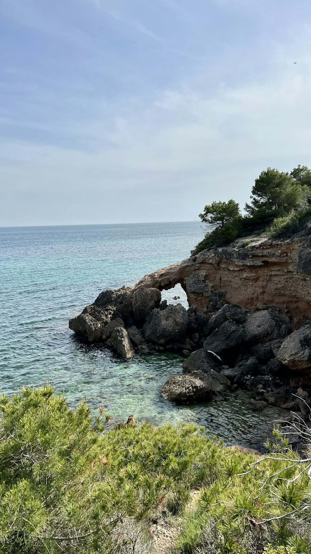 a rocky shore with a small arch in the middle of it