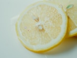 Close-up of crisp dried lemon slices glowing under soft light on a white background.