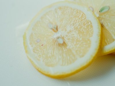 Close-up of crisp dried lemon slices glowing under soft light on a white background.