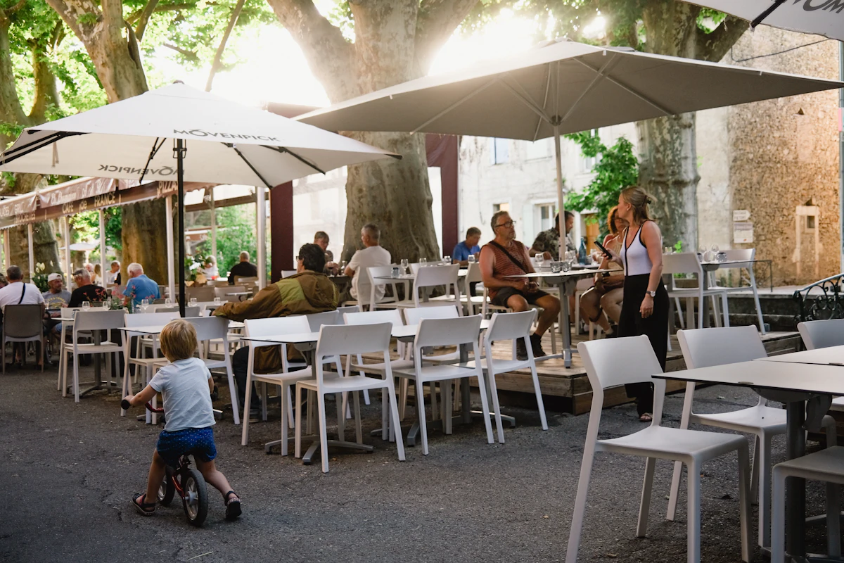 a group of people sitting at tables under umbrellas