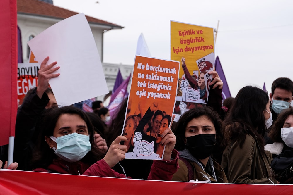 a group of people holding signs and wearing masks