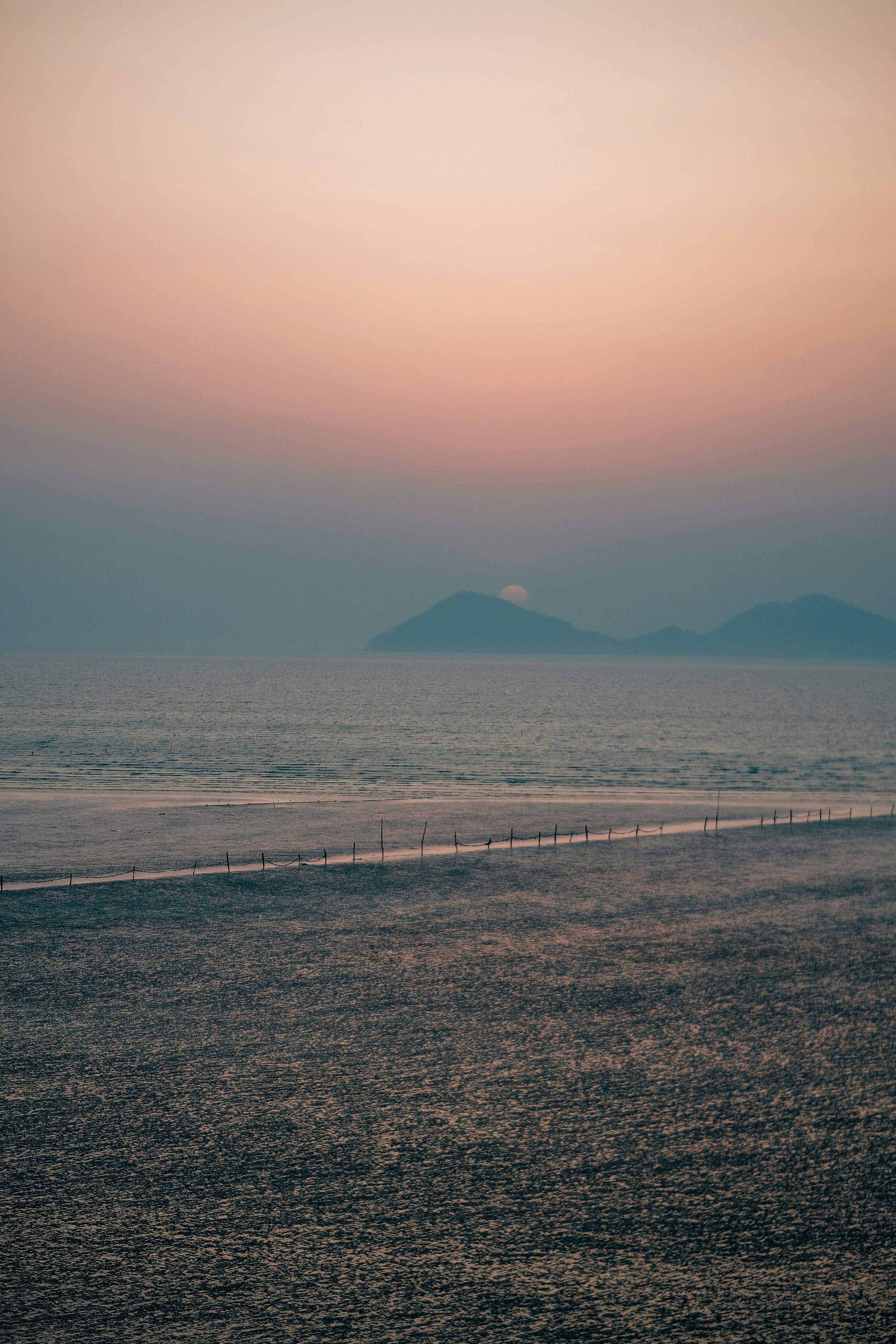 the sun is setting over the ocean and mountains