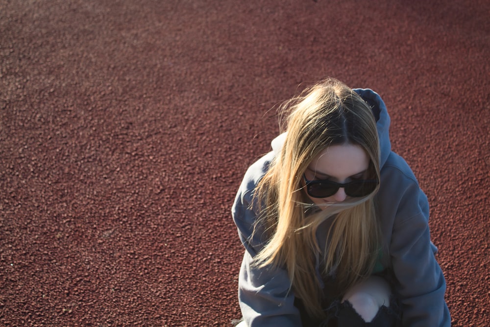 a woman sitting on a tennis court wearing sunglasses