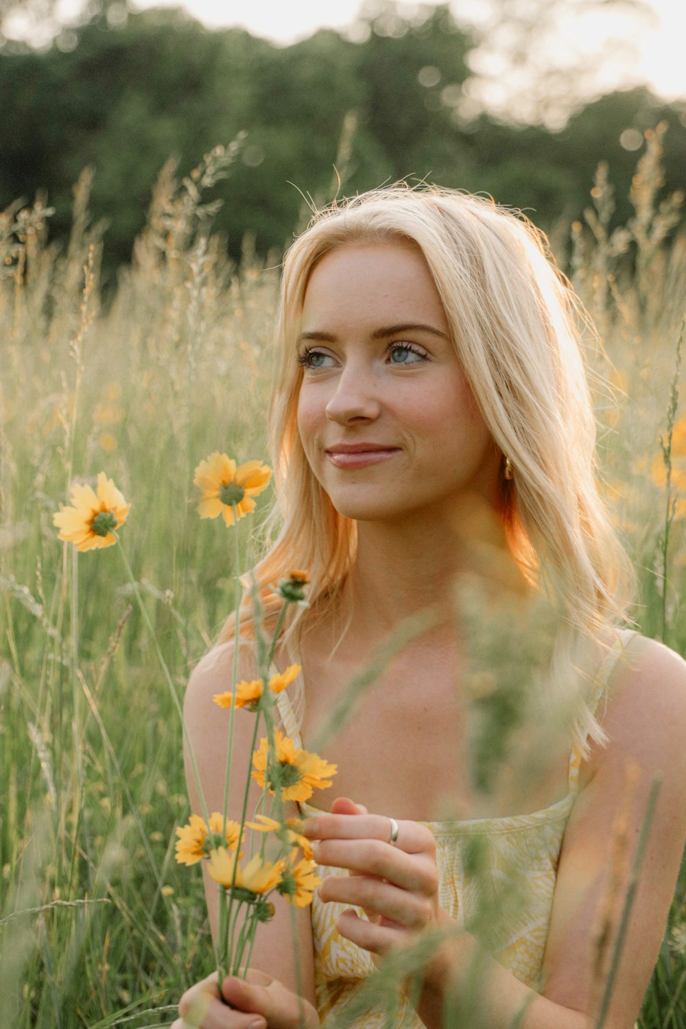 a beautiful blonde woman standing in a field of flowers