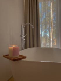 a candle sitting on top of a bathtub next to a window