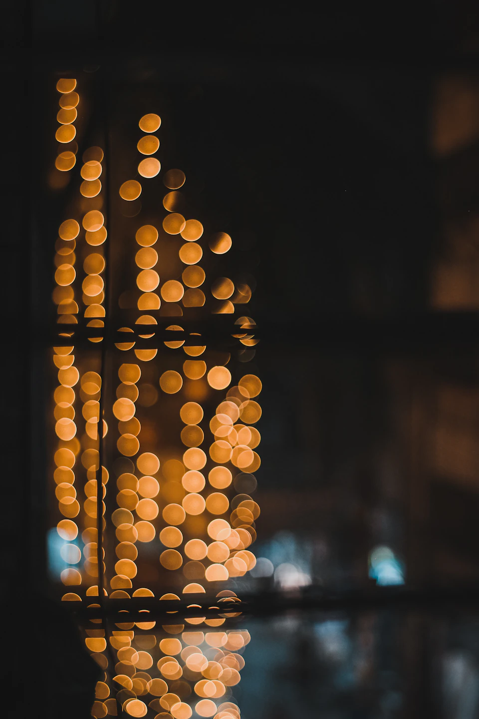 Window with city street view outside at night, illuminated by warm orange lights