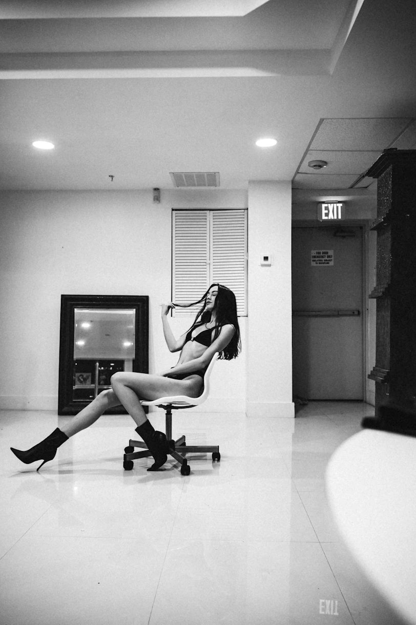 a woman on an adult chat line in black lingerie and boots sitting on a chair in a room